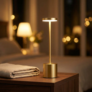 Lampe de table sans fil en métal doré allumée sur une table de chevet diffusant une lumière chaude
