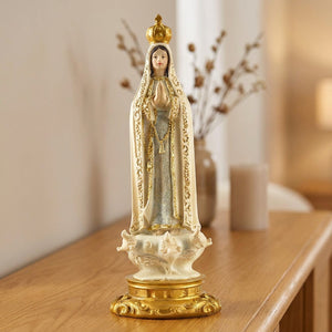 Statue de Notre-Dame de Fatima en résine crème et dorée posée sur une console en bois