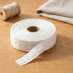 Galon fronceur blanc pour rideaux enroulé en rouleau avec poches à crochets visibles sur une surface claire