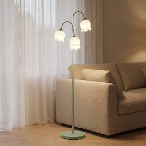 Lampadaire muguet vert à trois fleurs lumineuses blanches dans un salon chaleureux