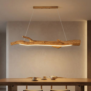 Lustre suspendu en résine noire imitant une branche allumé au dessus d'une table à manger dans un intérieur chaleureux