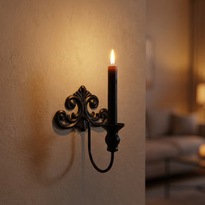 Bougeoir mural en métal noir de style baroque avec une bougie allumée fixé sur un mur