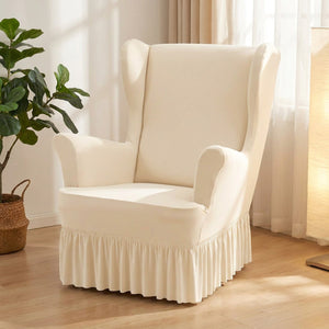 Housse de fauteuil à oreilles écrue avec jupe à volants installée dans un salon lumineux