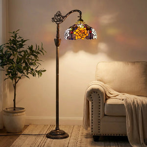 Lampadaire liseuse style Tiffany avec abat-jour en verre teinté à motif de roses ambrées allumé dans un salon cosy