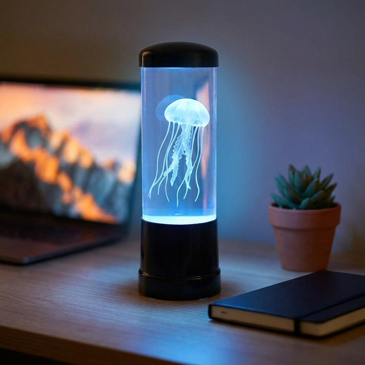 Lampe méduse USB allumée en bleu sur un bureau avec plante succulente