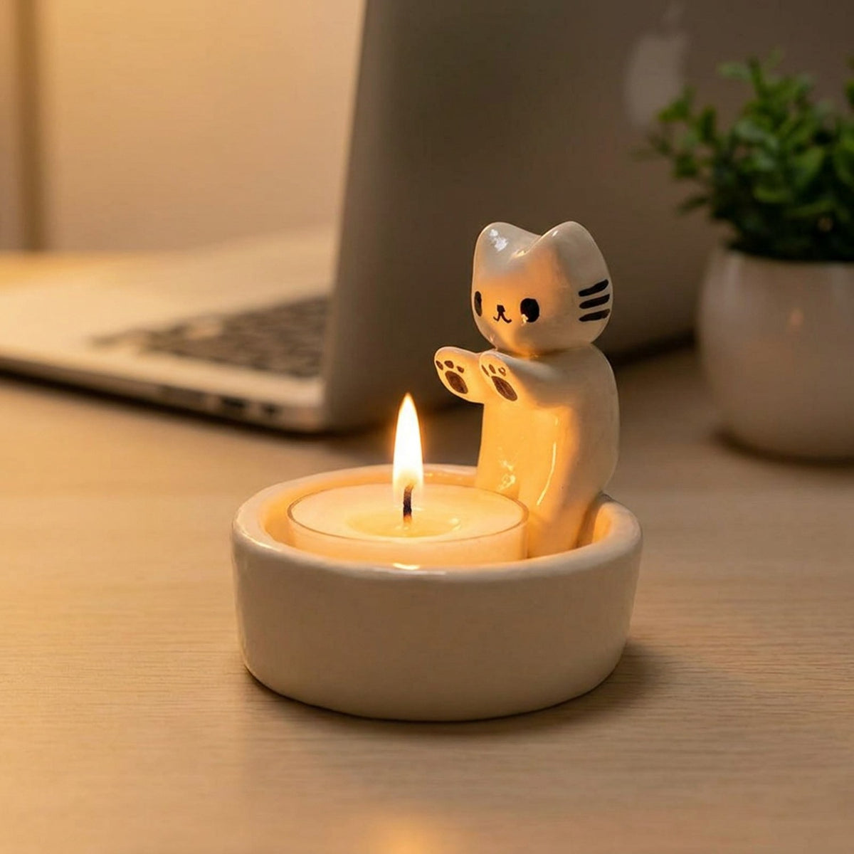 Bougeoir chat allumé sur un bureau en bois près d'un ordinateur portable