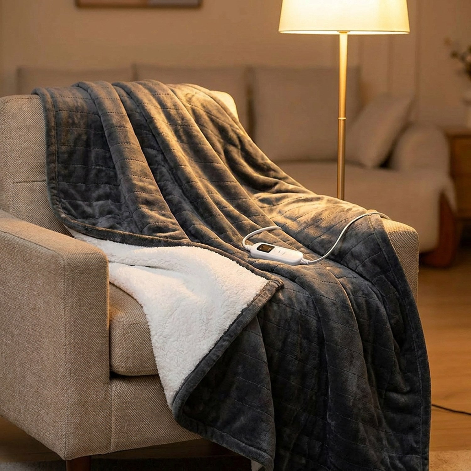 Couverture chauffante grise drapée sur un fauteuil dans un salon chaleureux le soir