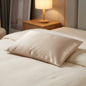 Taie d'oreiller en soie beige sur un lit dans une chambre moderne avec table de chevet