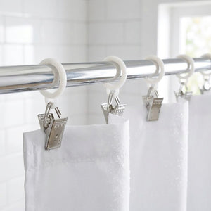 Rideau de douche blanc fixé à une tringle chromée grâce à des pinces à roulettes