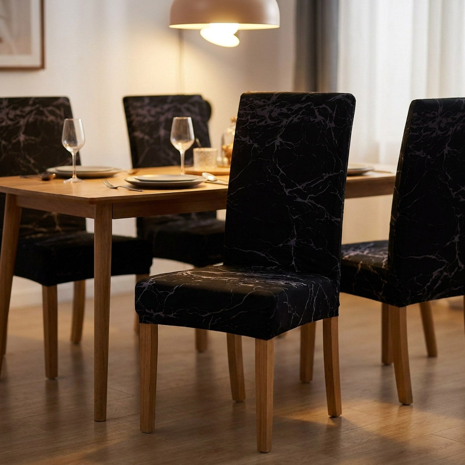 Table de salle à manger dressée avec plusieurs chaises habillées de housses marbre noir