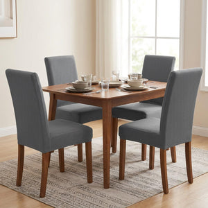 Quatre chaises de salle à manger habillées de housses grises autour d une table