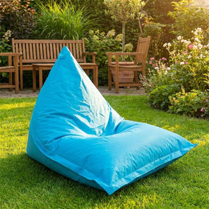 Pouf géant turquoise utilisé comme fauteuil dans un jardin