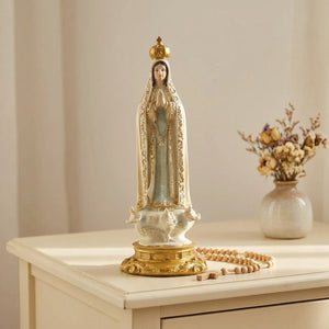 Figurine de Notre-Dame de Fatima sur une commode crème avec un chapelet et des fleurs séchées