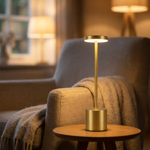 Lampe de table dorée posée sur une table d appoint près d un fauteuil cosy