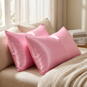 Deux taies d'oreiller en satin rose près d'une fenêtre lumineuse