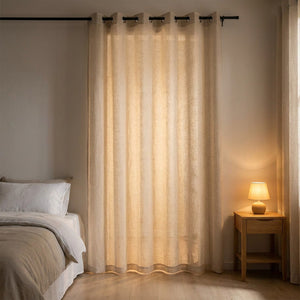 Voilage tulle beige dans une chambre cosy avec lit et lampe de chevet allumée
