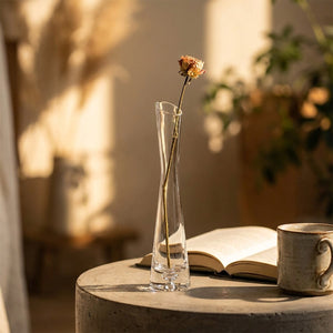 Vase soliflore en verre sur une table d'appoint à la lumière dorée avec un livre