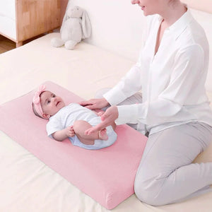 Maman changeant son bébé sur une housse de matelas à langer rose