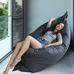 Personne allongée sur la housse de pouf géant noire sur un balcon extérieur