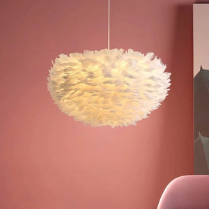 Suspension boule en plumes blanches allumée dans un salon aux tons roses