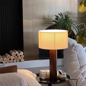 Lampe de table bois massif abat-jour plissé sur une table de chevet ronde près d'une cheminée