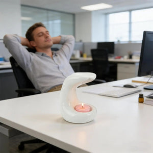 Brûle-parfum en céramique blanche posé sur un bureau dans une ambiance de détente