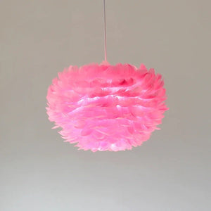Suspension boule en plumes roses allumée sur fond gris