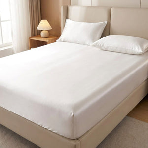 Drap housse satin blanc sur un lit fait avec deux oreillers assortis