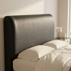 Housse de tête de lit effet cuir noir installée sur un lit dans une chambre lumineuse