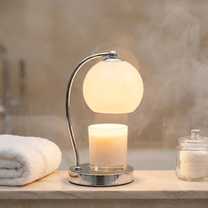 Lampe chauffe-bougie blanche sur une tablette de salle de bain avec serviette