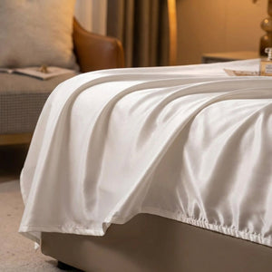 Détail du tissu satiné blanc drapé au pied du lit
