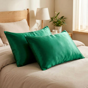 Deux taies d'oreiller en satin vert sur un lit
