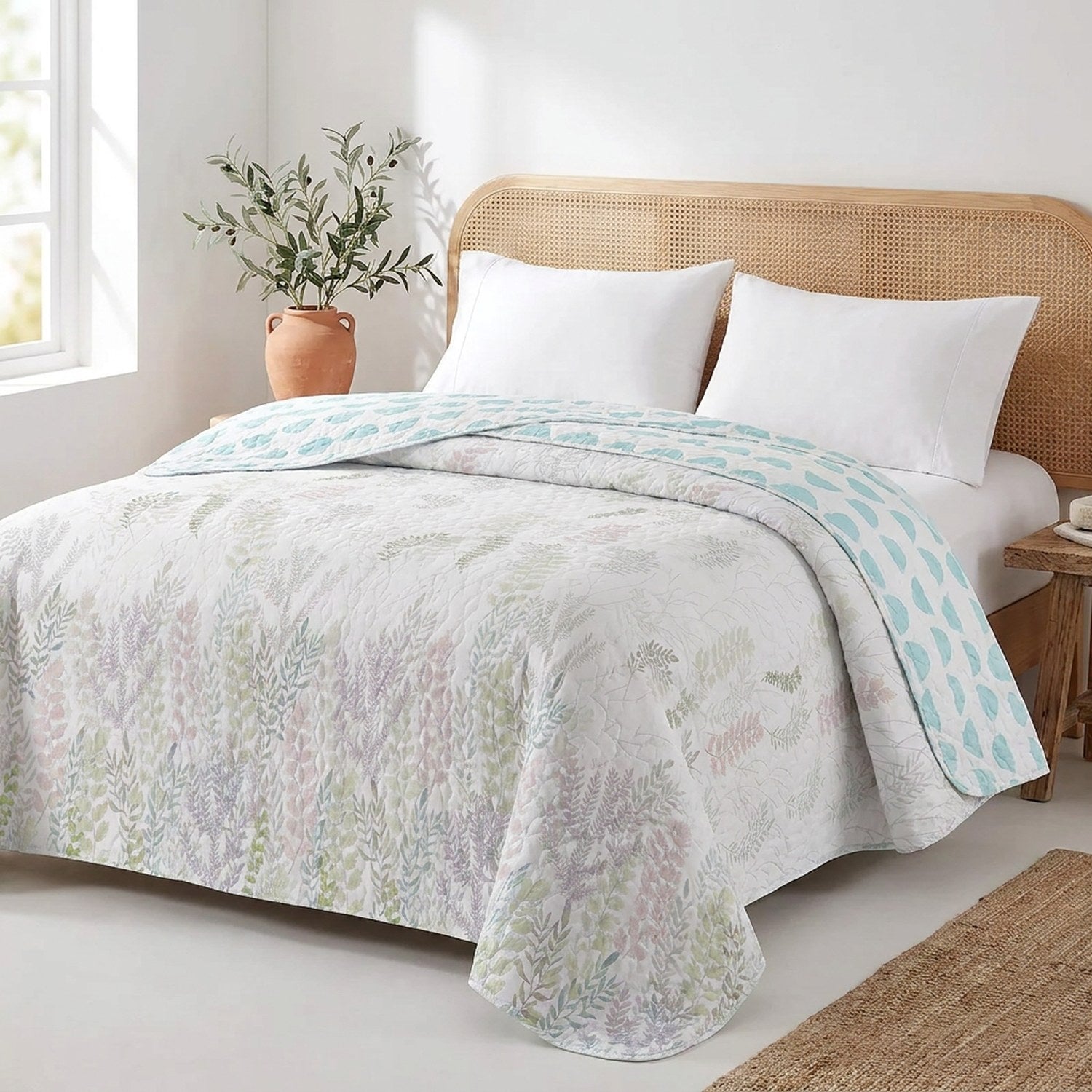 Jeté de lit réversible à feuillage pastel sur un lit dans une chambre côtière
