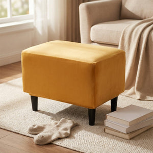 Housse de repose-pieds moutarde utilisée comme repose-pieds près d'un fauteuil lecture