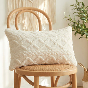 Housse de coussin lombaire en peluche blanc crème à relief géométrique sur un fauteuil en bois
