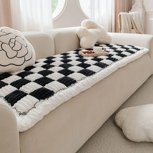 Un coussin chat cocooning épais posé sur un canapé, avec une surface matelassée formant un large espace moelleux où un chat peut s’allonger confortablement pour se reposer.