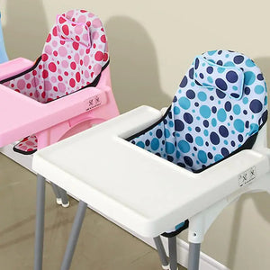 Deux coussins de chaise haute pliables pour bébé installés sur des chaises hautes, avec un design rembourré et des motifs ronds ludiques couvrant le dossier et l’assise.