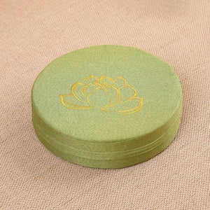 Coussin de sol rond en lin vert avec broderie décorative au centre, conçu pour offrir une assise confortable pour méditation ou détente.