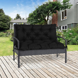 Coussin extérieur rectangulaire épais capitonné installé sur un banc de jardin en résine tressée, créant une assise moelleuse et accueillante sur une terrasse en bois.