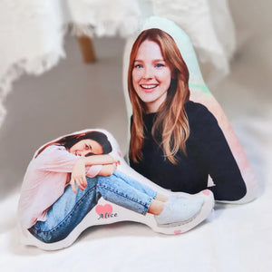 Un coussin personnalisé découpé à la forme d’une photo représentant une personne assise, posé sur un sol clair dans un intérieur doux et lumineux.