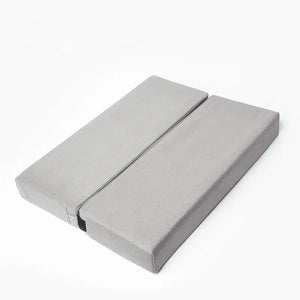 Un coussin yoga rectangulaire design pratique, pliable, posé sur un fond neutre avec une surface lisse et des lignes épurées, idéal pour la méditation et le bien-être