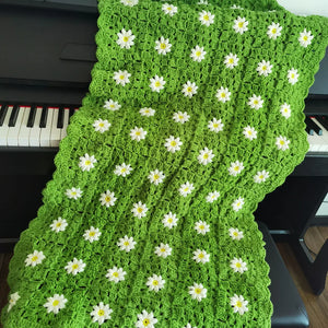 Un plaid crochet à motifs marguerites, avec des fleurs en relief réparties sur toute la surface, créant un rendu texturé et artisanal.