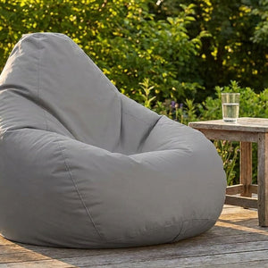 Pouf poire gris sur une terrasse en bois dans un jardin