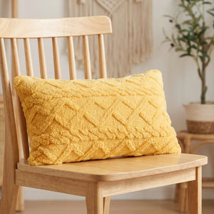 Housse de coussin lombaire en peluche jaune moutarde à relief géométrique sur un fauteuil en bois