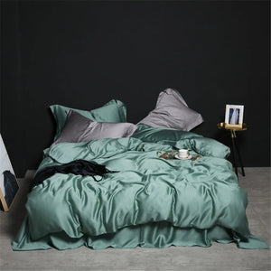 Une parure de lit luxe finition satinée aux reflets lumineux, présentée sur un lit avec plusieurs oreillers et une couette au tissu fluide, dans une chambre à l’ambiance élégante et minimaliste.