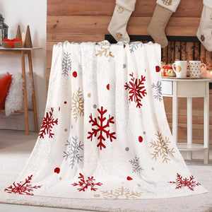 Un plaid Noël ambiance festive avec motifs de flocons hivernaux, posé devant une cheminée décorée avec des chaussettes de Noël dans un salon chaleureux.