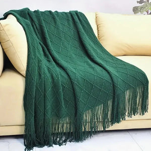 Un plaid Noël avec franges au tissage texturé, délicatement posé sur un canapé clair, créant une ambiance chaleureuse et cocooning dans un salon lumineux.