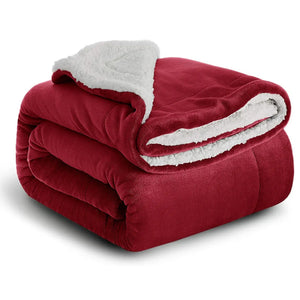 Un plaid cocooning double face plié, avec une face extérieure lisse et une face intérieure épaisse et duveteuse visible, créant un aspect particulièrement moelleux et chaleureux.