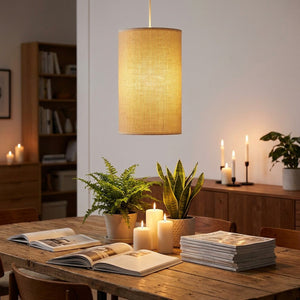 Abat-jour cylindrique en lin beige en suspension au-dessus d'une table à manger, ambiance chaleureuse