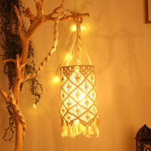 Abat-jour en macramé allumé suspendu à une branche bohème avec guirlande lumineuse